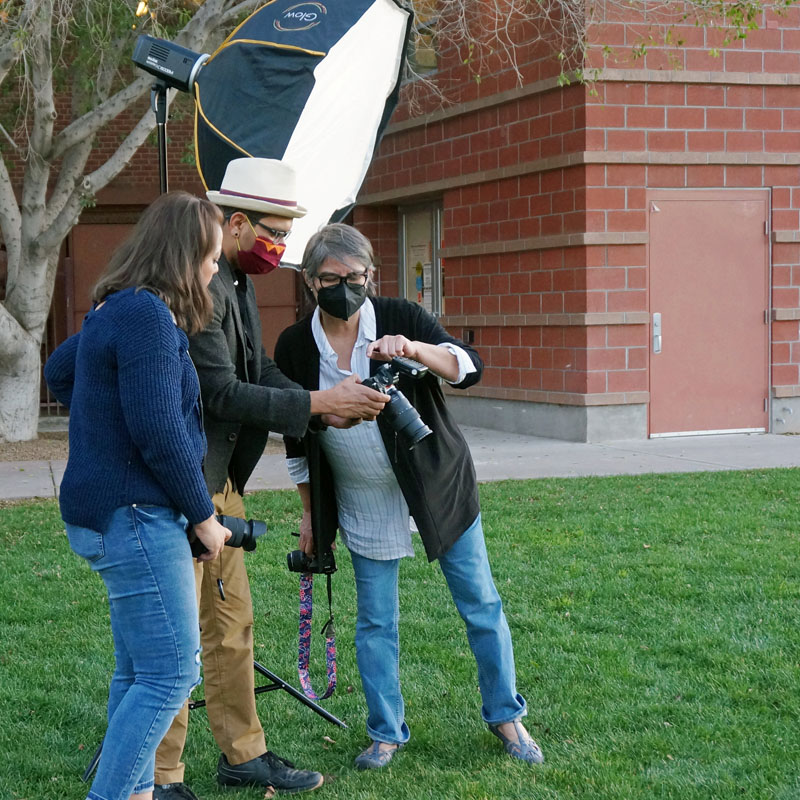 Teaching artists and two students in an outdoor photography class with lighting and camera equipment