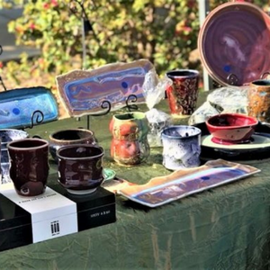 Outdoor table display of ceramic cups, plates, and bowls