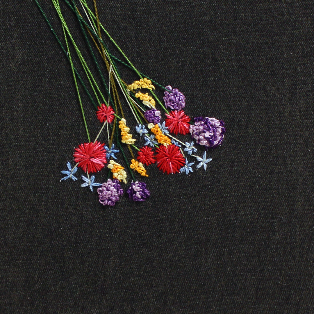 Embroidery of wildflowers of different colors against a black background
