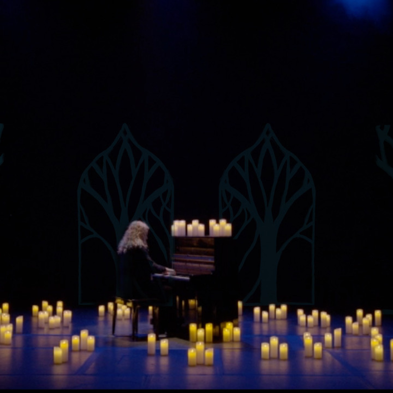 David Arkenstone at piano on stage surrounded by candlelight